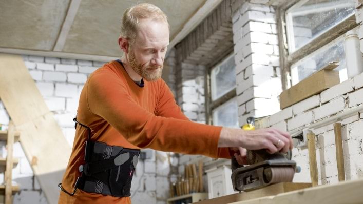 Volker with the Dyneva back orthosis working with wood in his workshop.