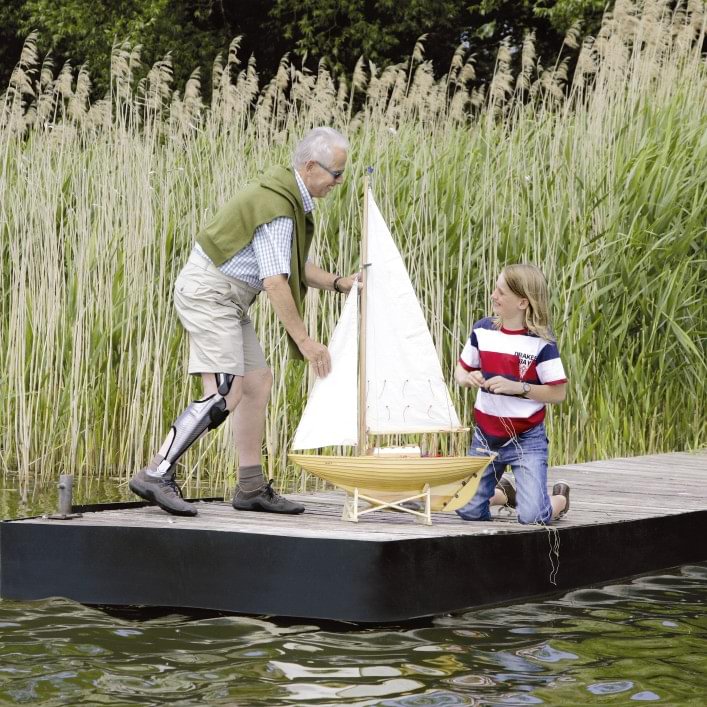 Peter with E-MAG Active orthosis and child playing with a sailboat.