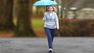 User with C-Leg prosthesis walking in the rain with an umbrella.