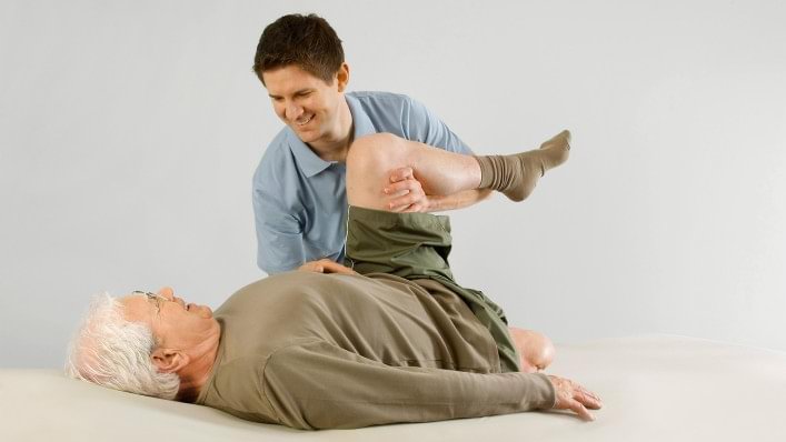 therapist working with an amputee patient on stretching his leg