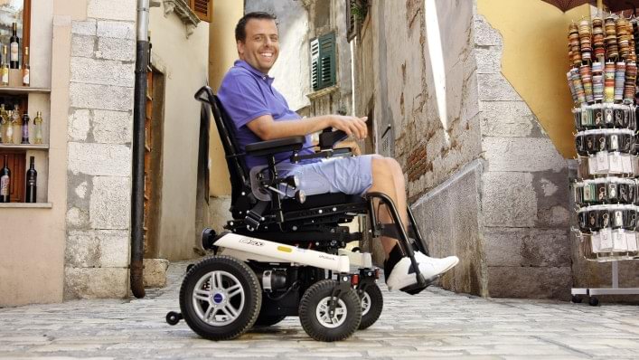 Un homme en fauteuil roulant, en promenade dans la vieille ville
