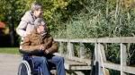 Ottobock manual wheelchair with channel forearm support: attendant pushes user across a wooden bridge