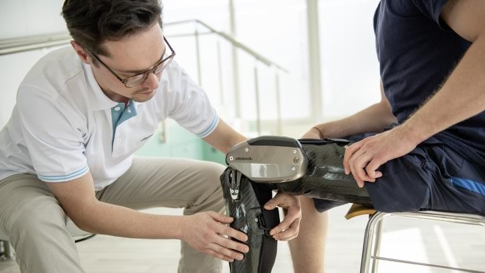 A practitioner helps adjust a C-Brace on a patient's leg