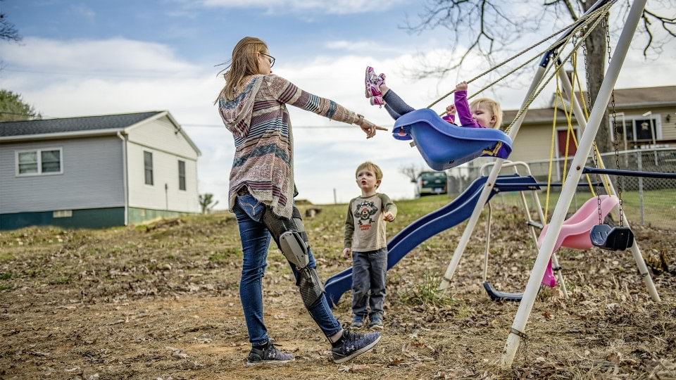 Hannah, usuaria de C-Brace®, juega con sus hijos en un columpio. 