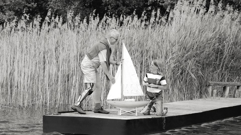 Peter with E-MAG Active orthosis and child playing with a sailboat.