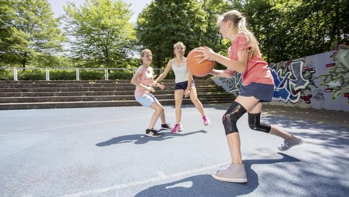 A girl plays basketball with Patella Pro.