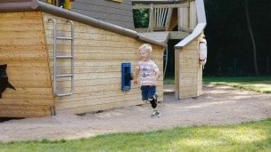Niño corriendo por un patio de recreo.  Lleva la WalkOn Reaction junior, una ortesis dinámica de tobillo-pie de Ottobock, en su pierna izquierda