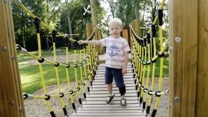 Niño cruzando un puente colgante en un parque infantil con WalkOn Reaction junior, una ortesis dinámica de tobillo-pie de Ottobock