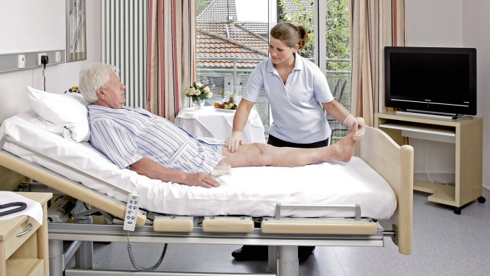 The therapist performs initial mobilisation exercises with the amputee at the hospital bed.
