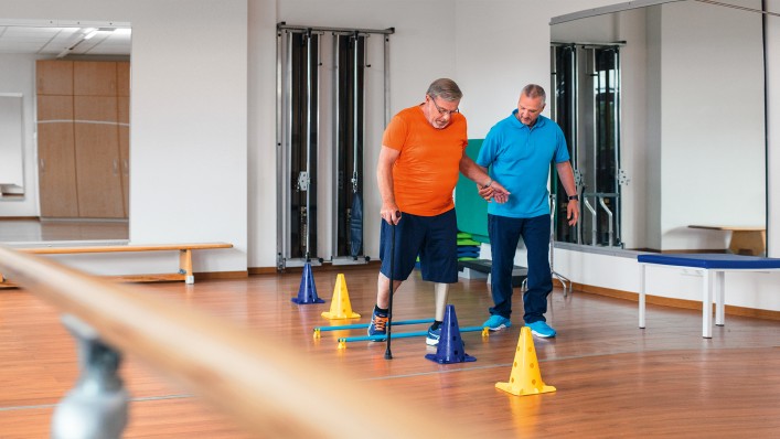 Jednostranně amputovaný Detlef spolu s terapeutem Markusem cvičí chůzi v gymnastické místnosti.