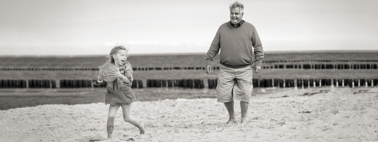 Herr Flügel spielt mit seiner Enkelin am Strand