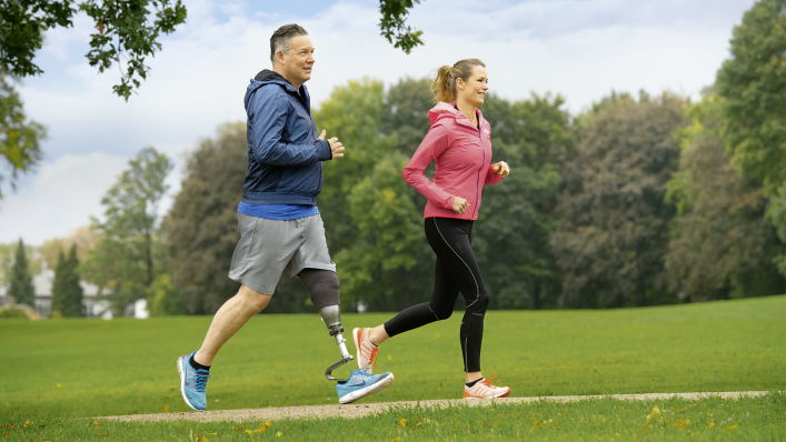 User of the Quickchange adapter for changing prosthetic feet running in the park with his partner.