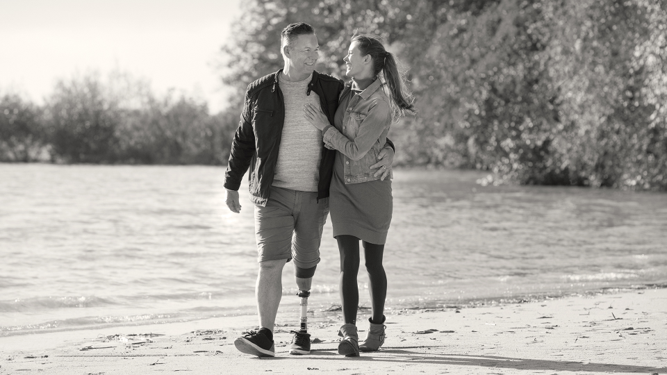 User of the Quickchange adapter for changing prosthetic feet walking on the beach with his partner.