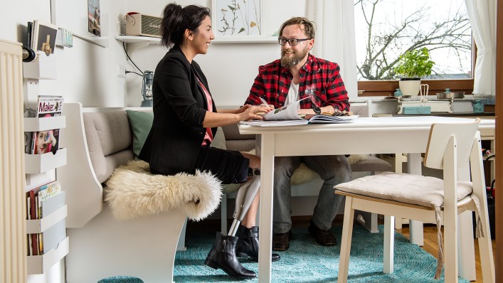 The C-Leg user is sitting at the kitchen table with her friend.