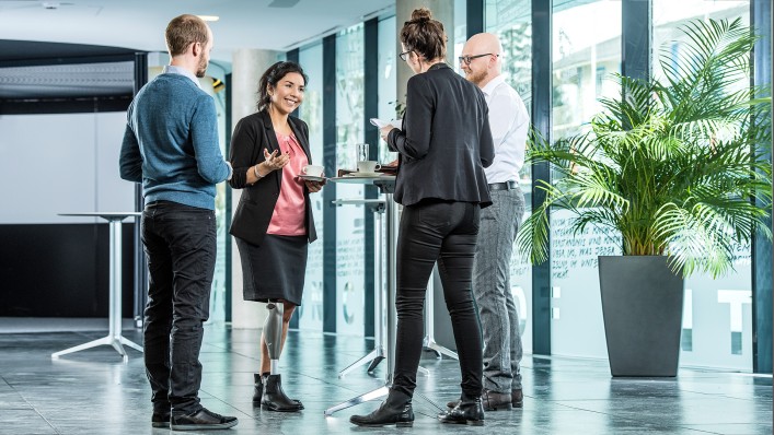 A C-Leg user standing among her colleagues at the morning stand-up meeting.