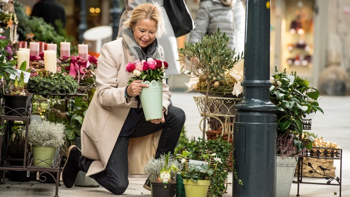 Sita kneeling outside the flower shop with her Functional Cosmesis.