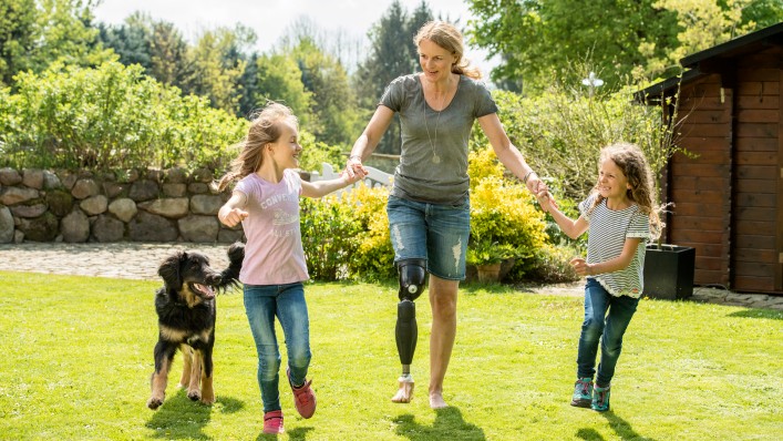 Genium X3 user Kerstin plays with her children and dog in the garden.