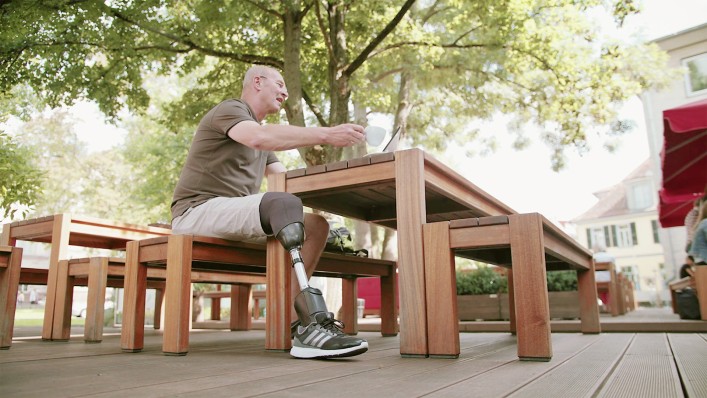 Carsten sits relaxed in the café with his Empower prosthetic foot.