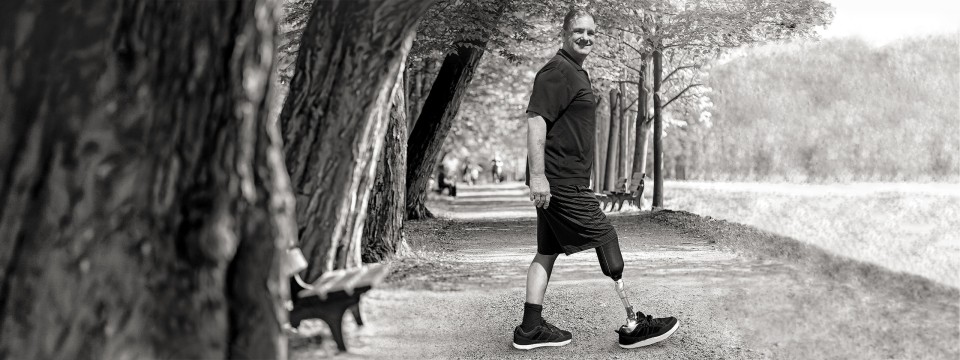 Danny geht mit seinem Maverick Comfort AT Prothesenfuß auf einem Waldweg spazieren.