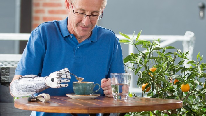 A bebionic prosthetic hand user stirring his cappuccino using the key grip. 