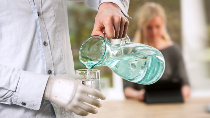 Sjaak pours himself a glass of water. The translucent prosthesis glove puts the prosthetic hand on stage