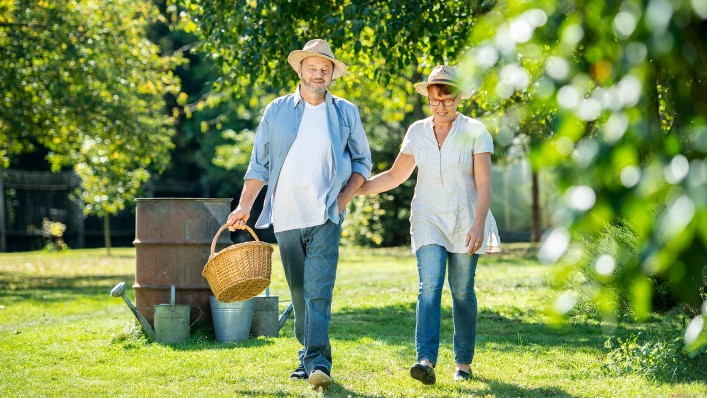 Frau und Mann, der zwei Prothesen mit DVS (Dynamic Vacuum System) trägt, stehen gemeinsam unter einem Apfelbaum und lächeln sich freudig an