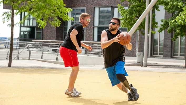 Portatore di protesi che gioca a basket in un playground