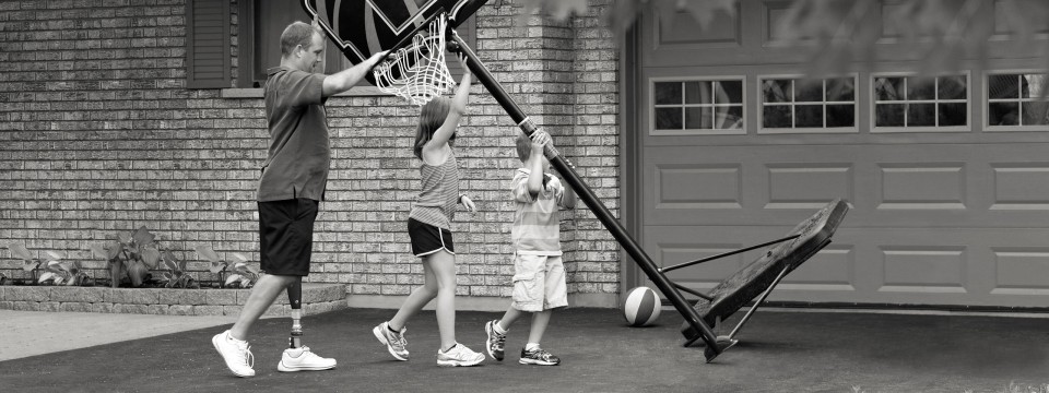 Jonathan with C-Leg prosthesis setting up a basketball basket to play with his children.